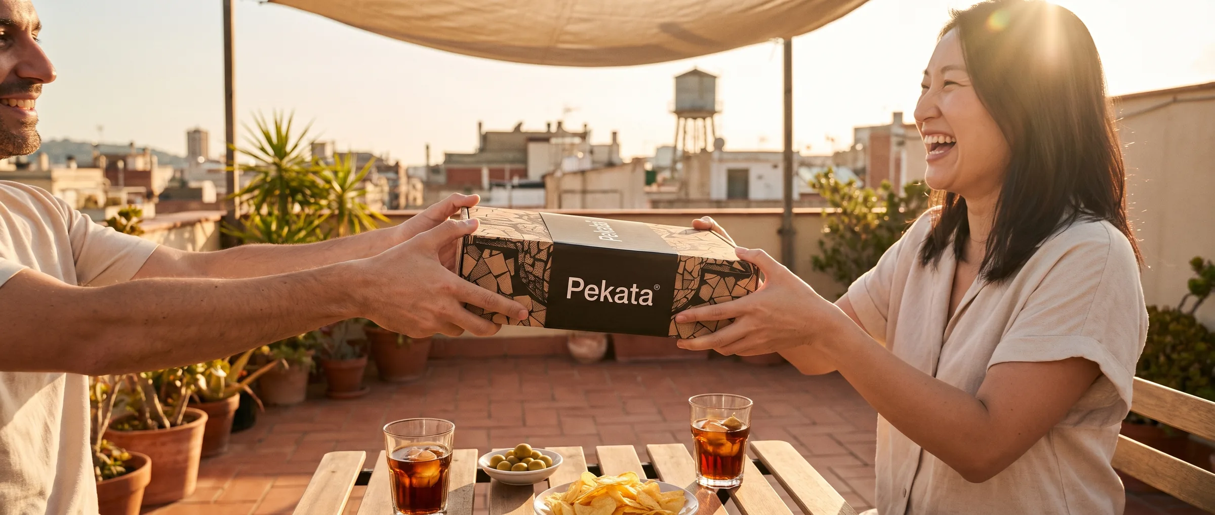 Two friends handing over a Pekata box on a Barcelona rooftop